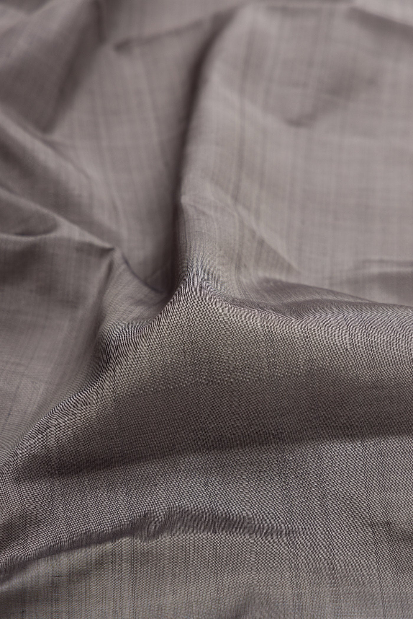 Close up of Grey Kanjivaram Silk Saree with Plain Body and Zari Border.  displaying folds