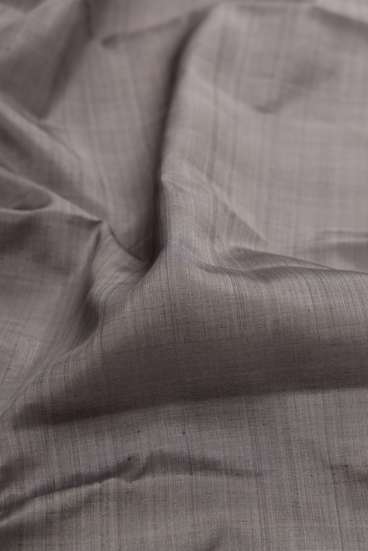 Close up of Grey Kanjivaram Silk Saree with Plain Body and Zari Border.  displaying folds