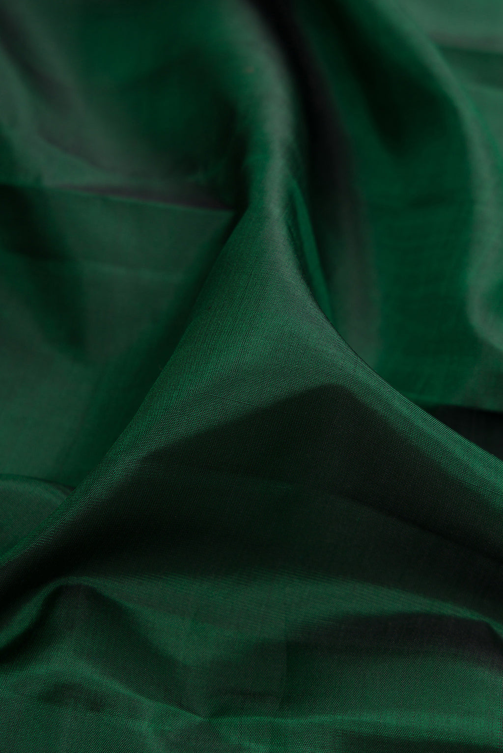 Close up of Bottle Green Kanjivaram Silk Saree with Plain Body and Zari Border.  displaying folds