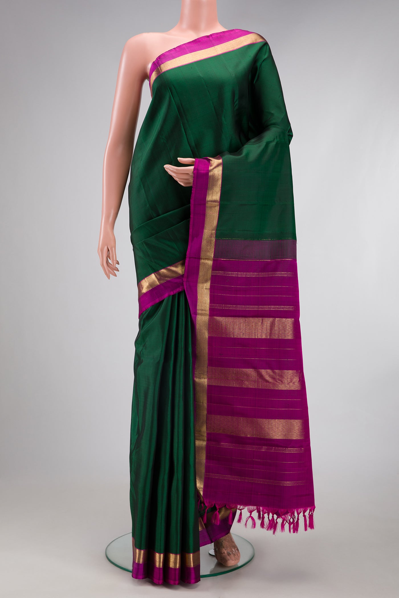Bottle Green Kanjivaram Silk Saree with Plain Body and Zari Border.  displayed on a mannequin