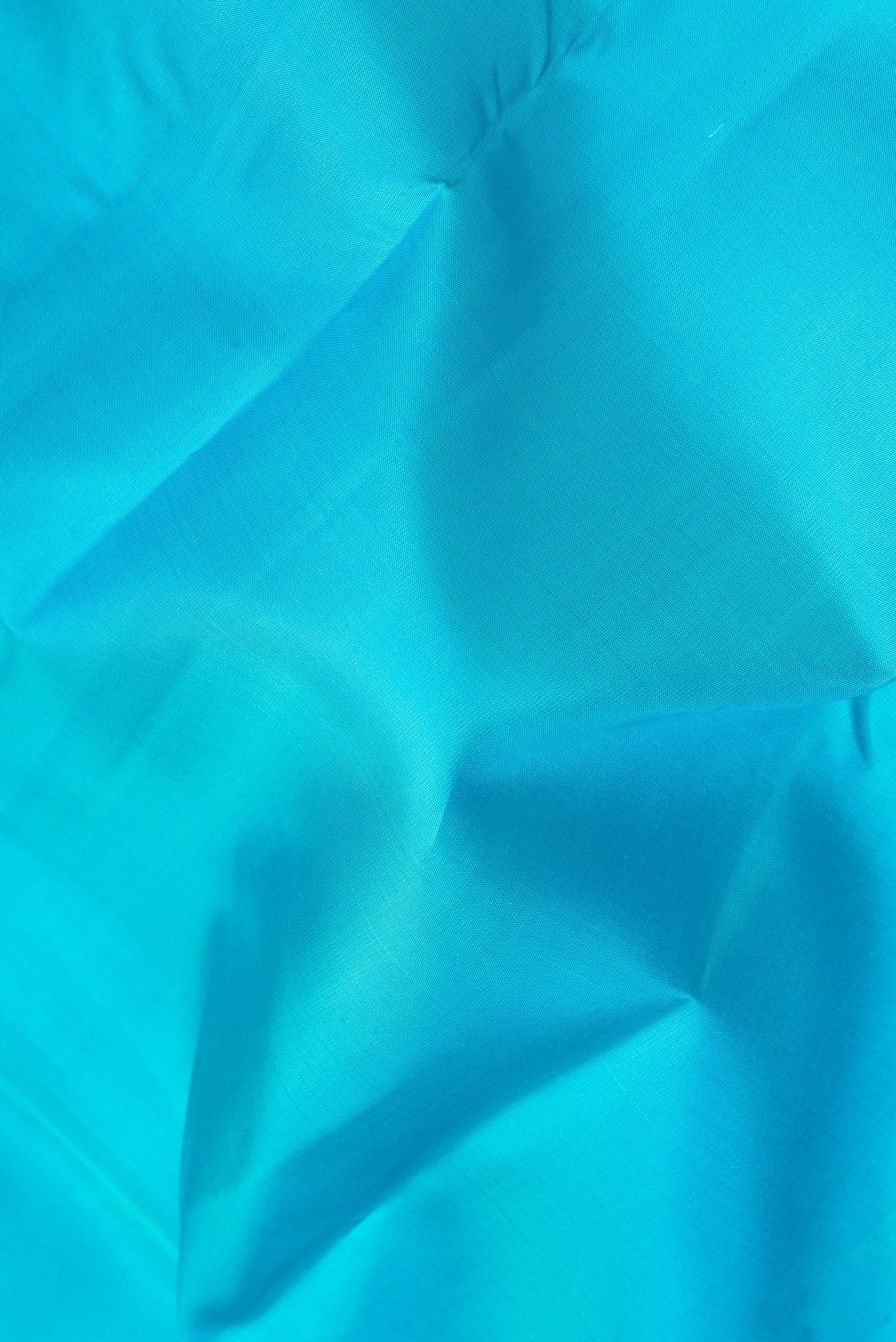 Close up of Light Blue Kanjivaram Silk Saree with Plain Body and Zari Border.  displaying folds