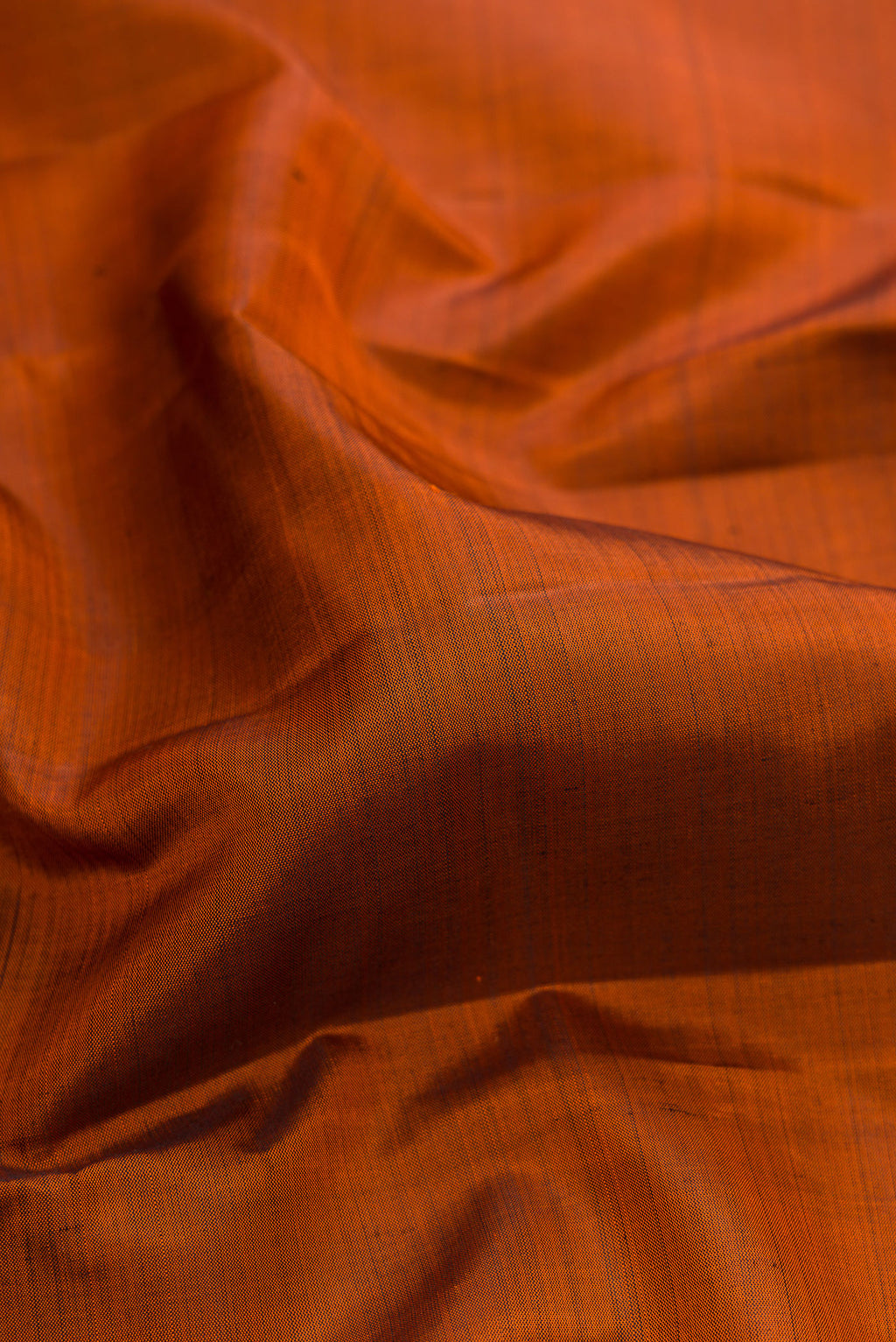 Close up of Rust Kanjivaram Silk Saree with Plain Body and Zari Border.  displaying folds