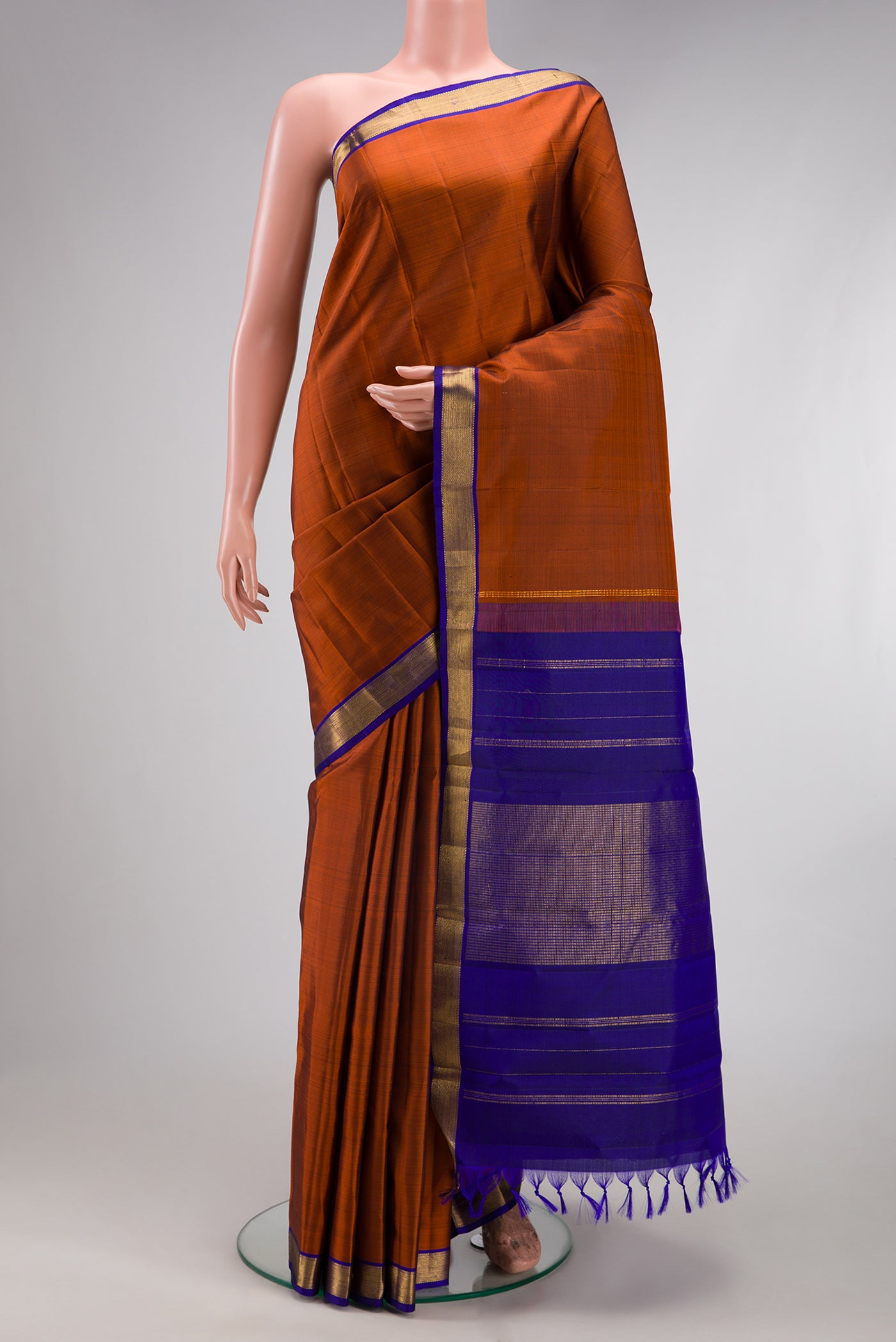 Rust Kanjivaram Silk Saree with Plain Body and Zari Border.  displayed on a mannequin