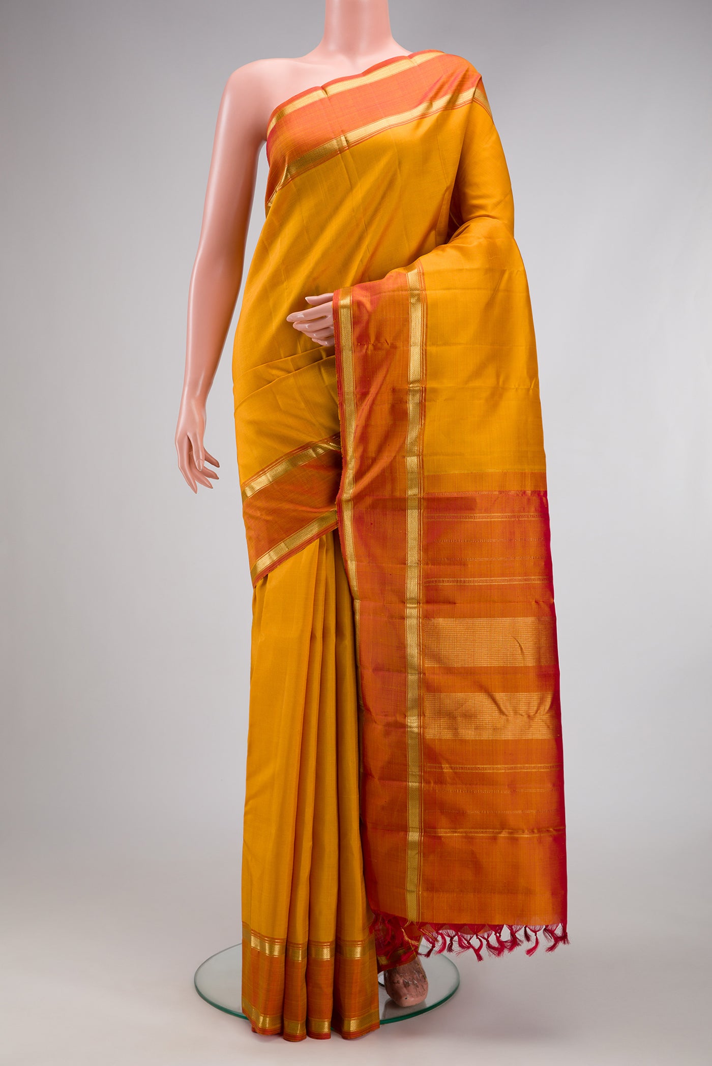 Mustard Kanjivaram Silk Saree with Plain Body and Zari Border.  displayed on a mannequin