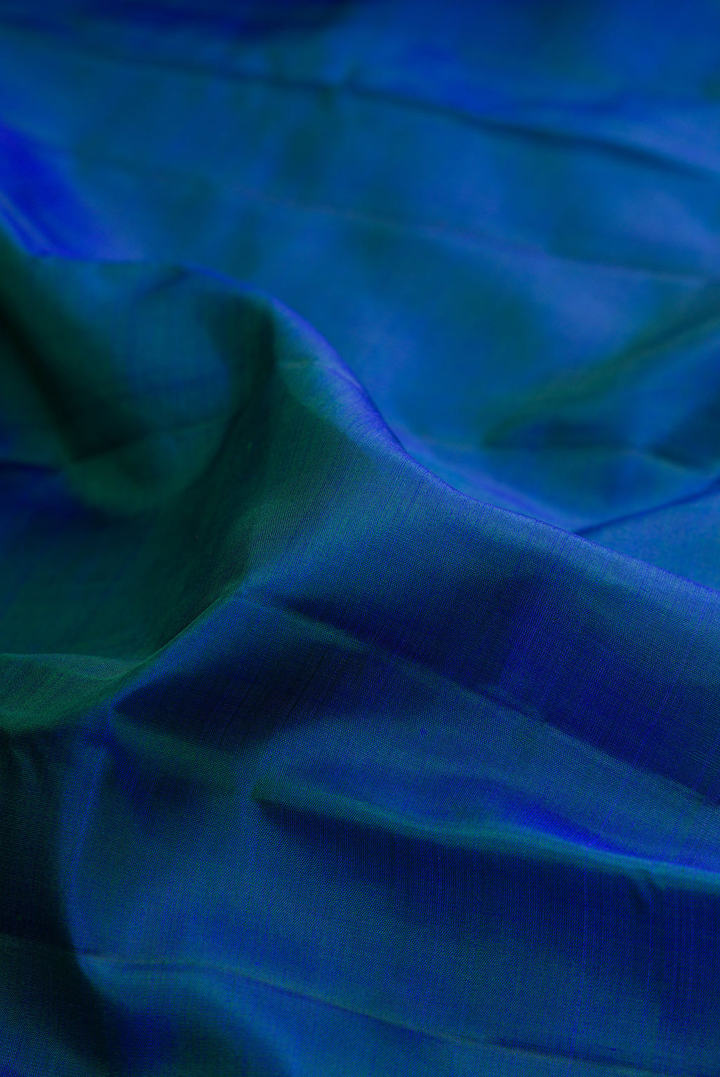 Close up of Peacock Blue Kanjivaram Silk Saree with Plain Body and Zari Border.  displaying folds