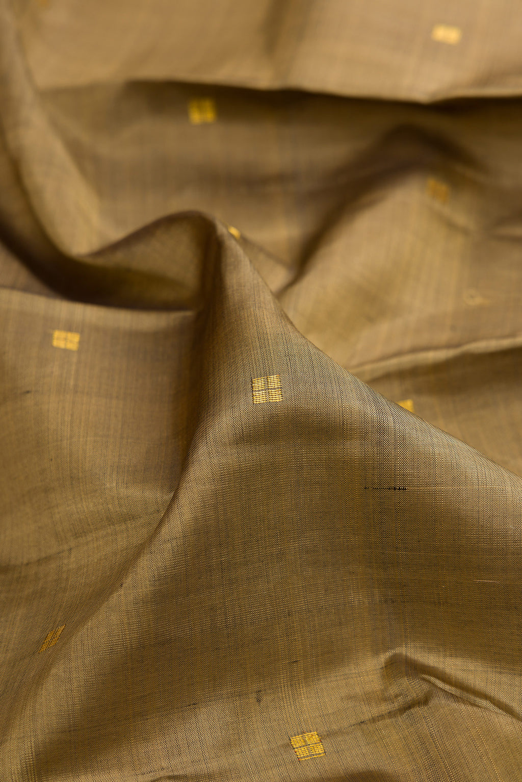 Close up of Dark Beige Kanjivaram Silk Saree with Zari Butta on the body and Zari Border.  displaying folds