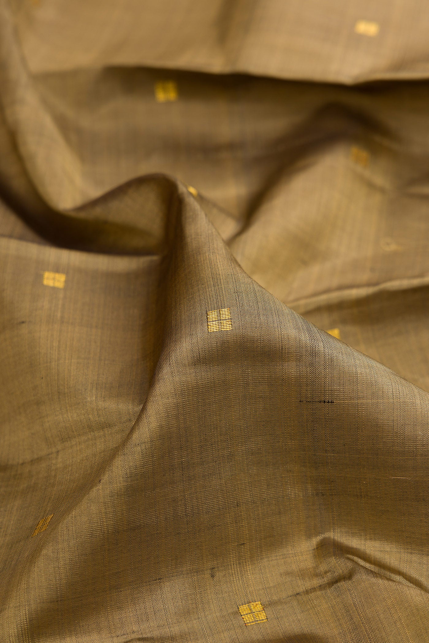 Close up of Dark Beige Kanjivaram Silk Saree with Zari Butta on the body and Zari Border.  displaying folds
