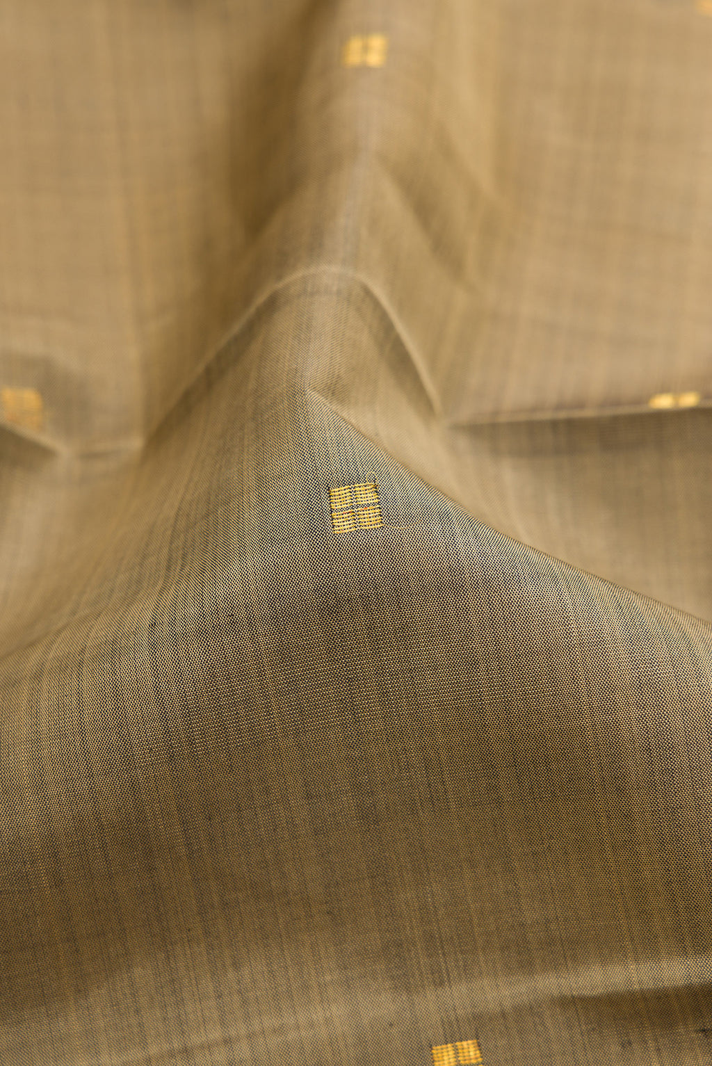 Close up of Dark Beige Kanjivaram Silk Saree with Zari Butta on the body and Zari Border.  displaying folds