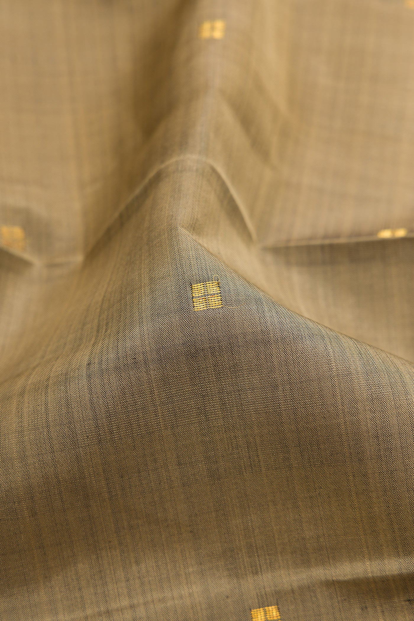 Close up of Dark Beige Kanjivaram Silk Saree with Zari Butta on the body and Zari Border.  displaying folds