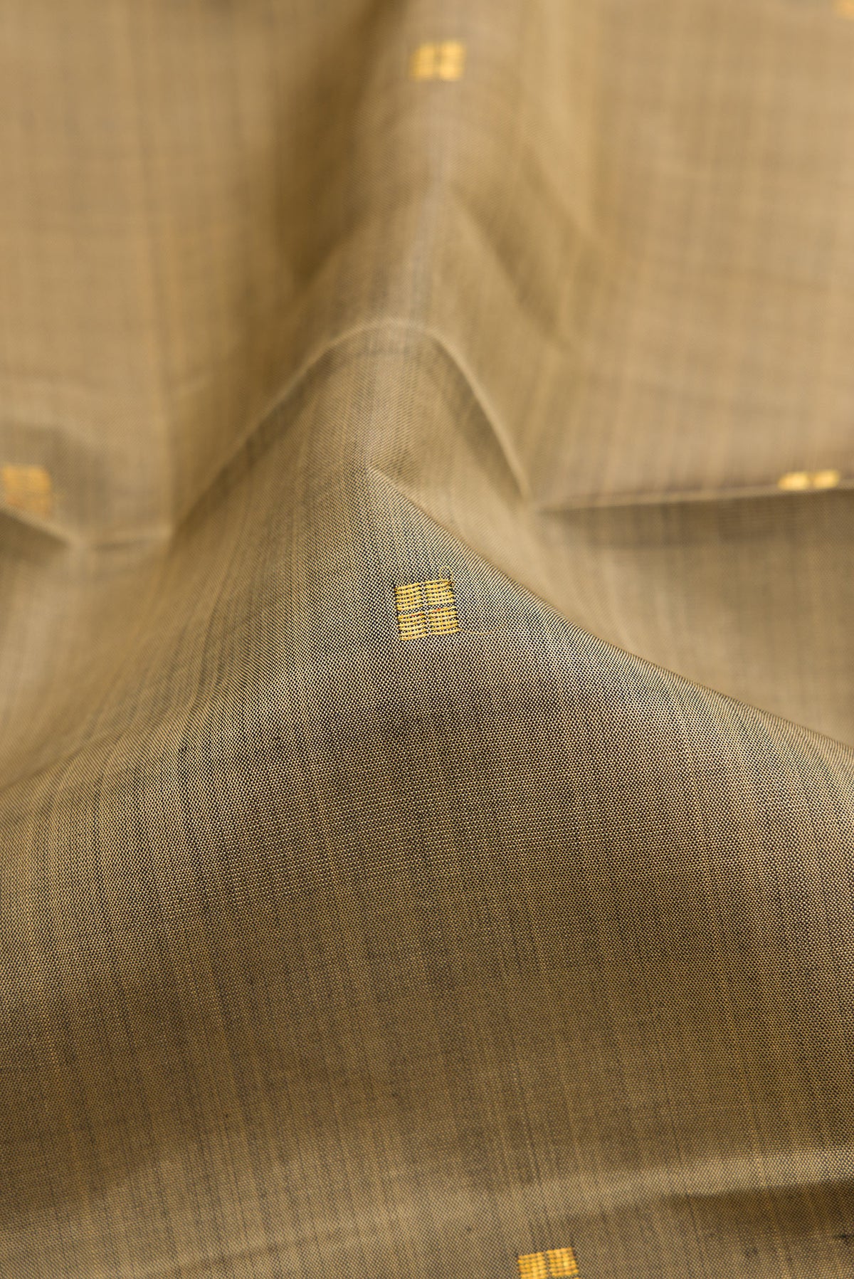 Close up of Dark Beige Kanjivaram Silk Saree with Zari Butta on the body and Zari Border.  displaying folds