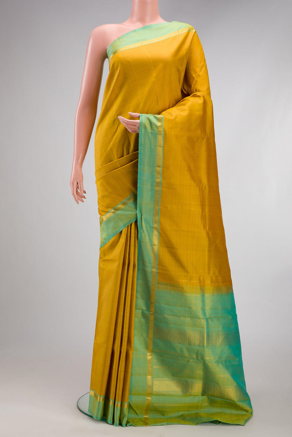 Mustard Kanjivaram Silk Saree with Plain Body and Zari Border.  displayed on a mannequin