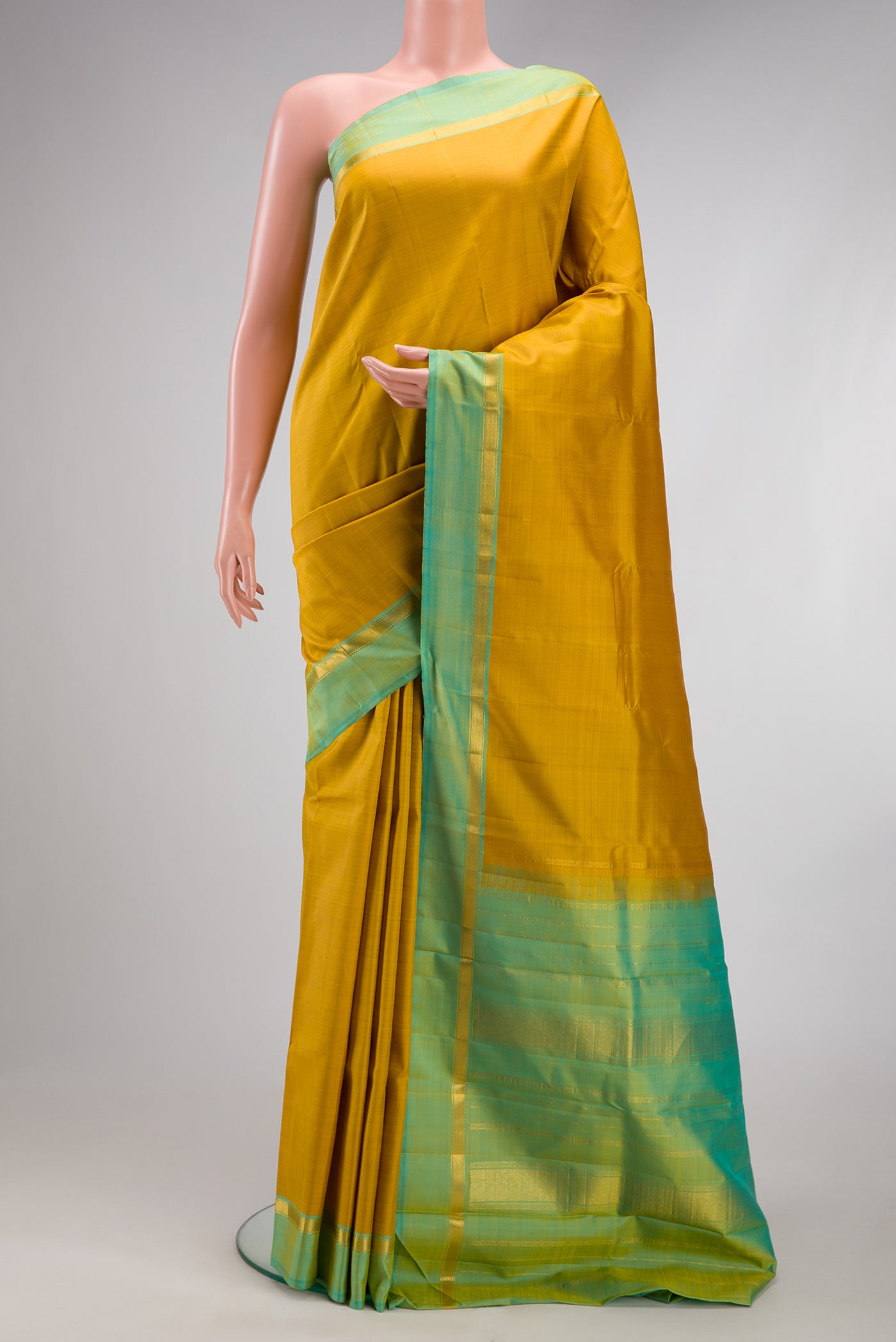 Mustard Kanjivaram Silk Saree with Plain Body and Zari Border.  displayed on a mannequin