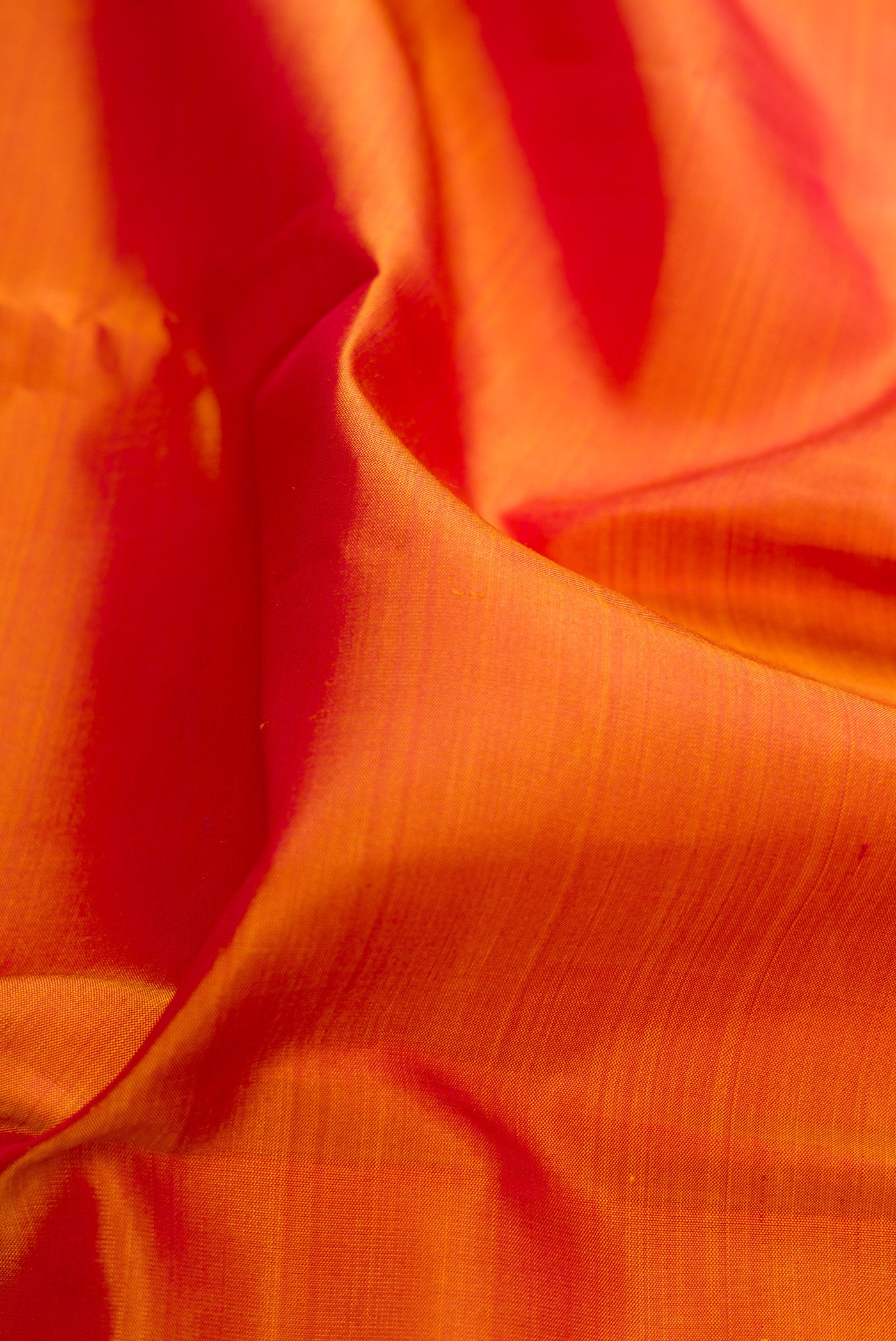 Close up of Brick Orange Kanjivaram Silk Saree with Plain Body and Zari Border.  displaying folds
