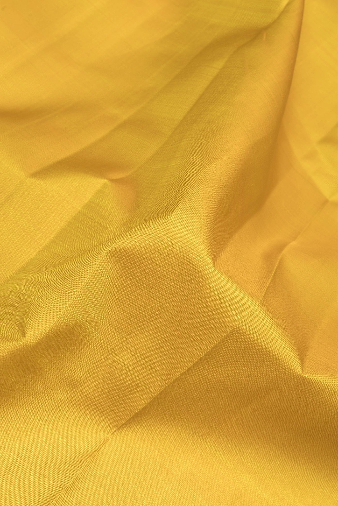 Close up of Lemon Yellow Kanchipuram Silk Saree with Plain Body and Zari Border.  displaying folds