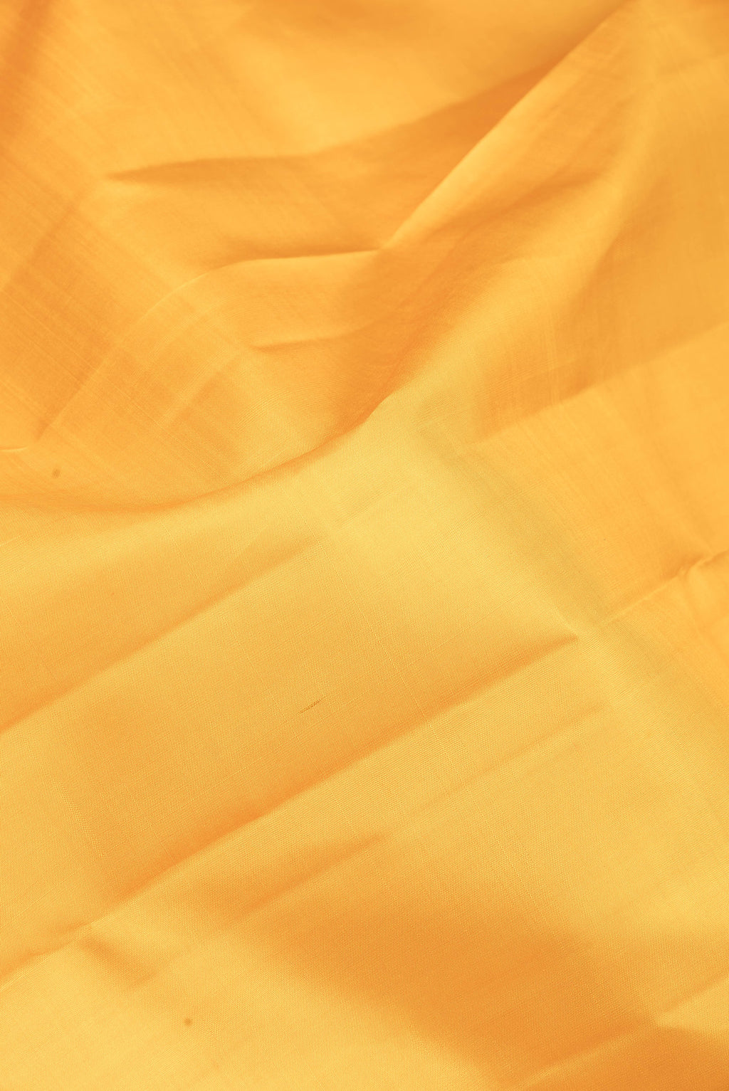 Close up of Yellow Kanchipuram Silk Saree with Plain Body and Zari Border.  displaying folds
