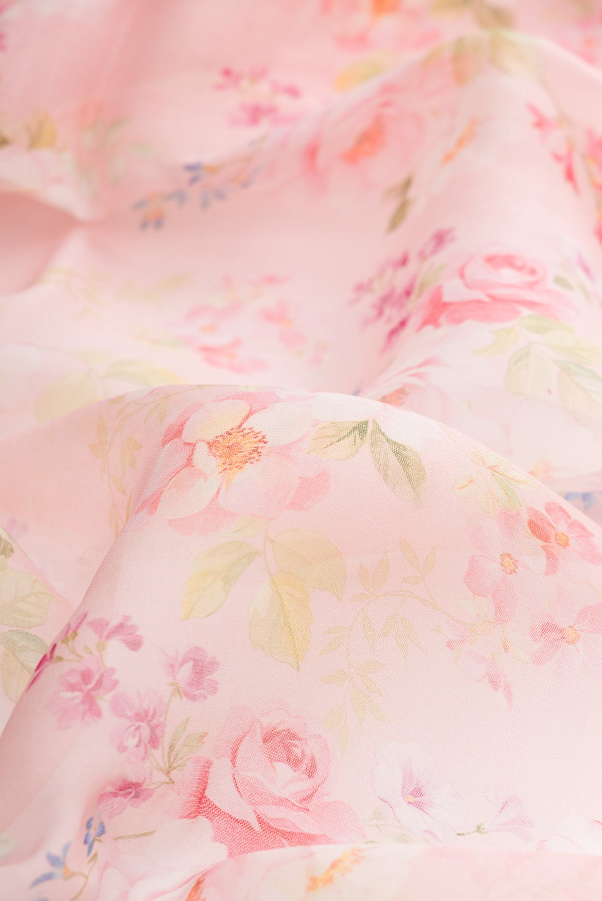 Close up of Pink Organza Saree with Floral Print on the body and Zari Border.  displaying folds
