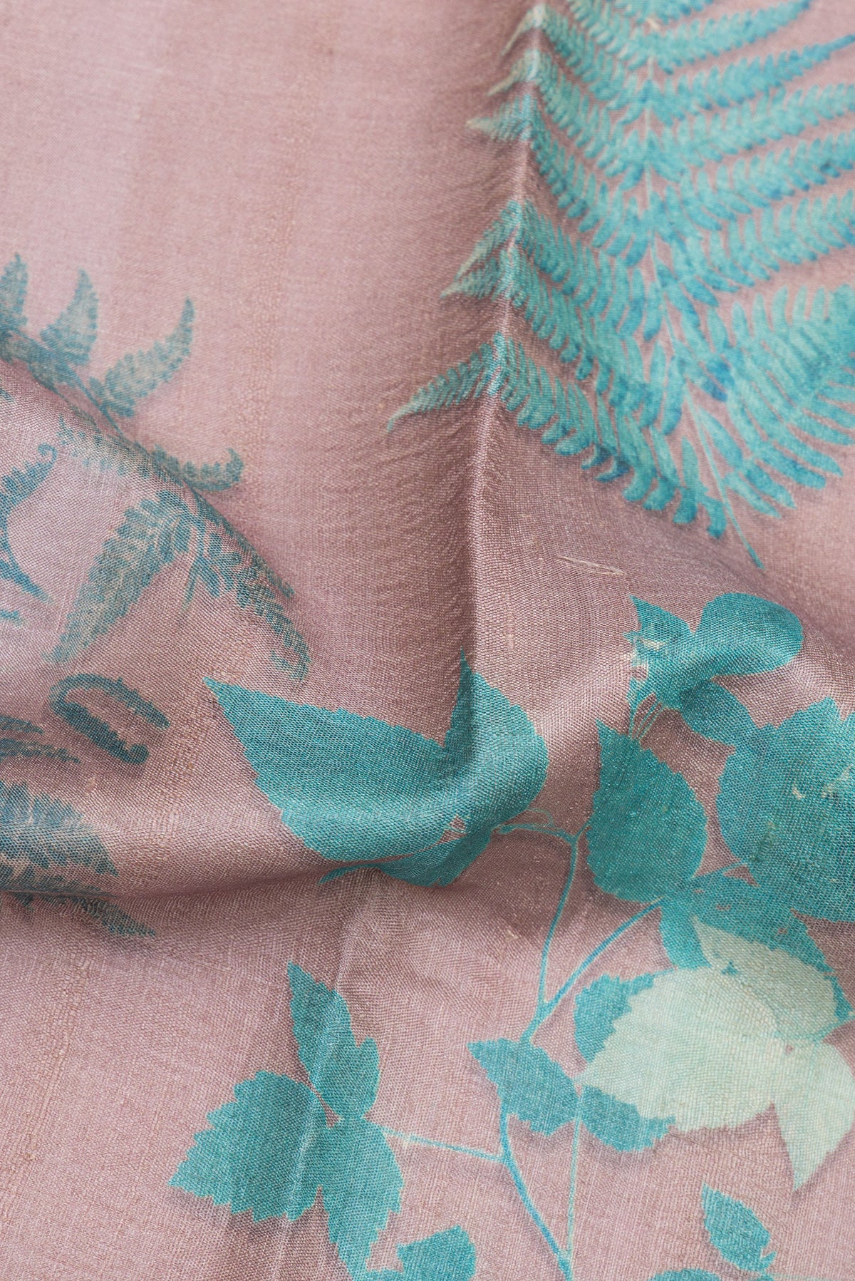 Close up of Rose Gold Tussar Saree with Floral Print on the body and Zari Border.  displaying folds