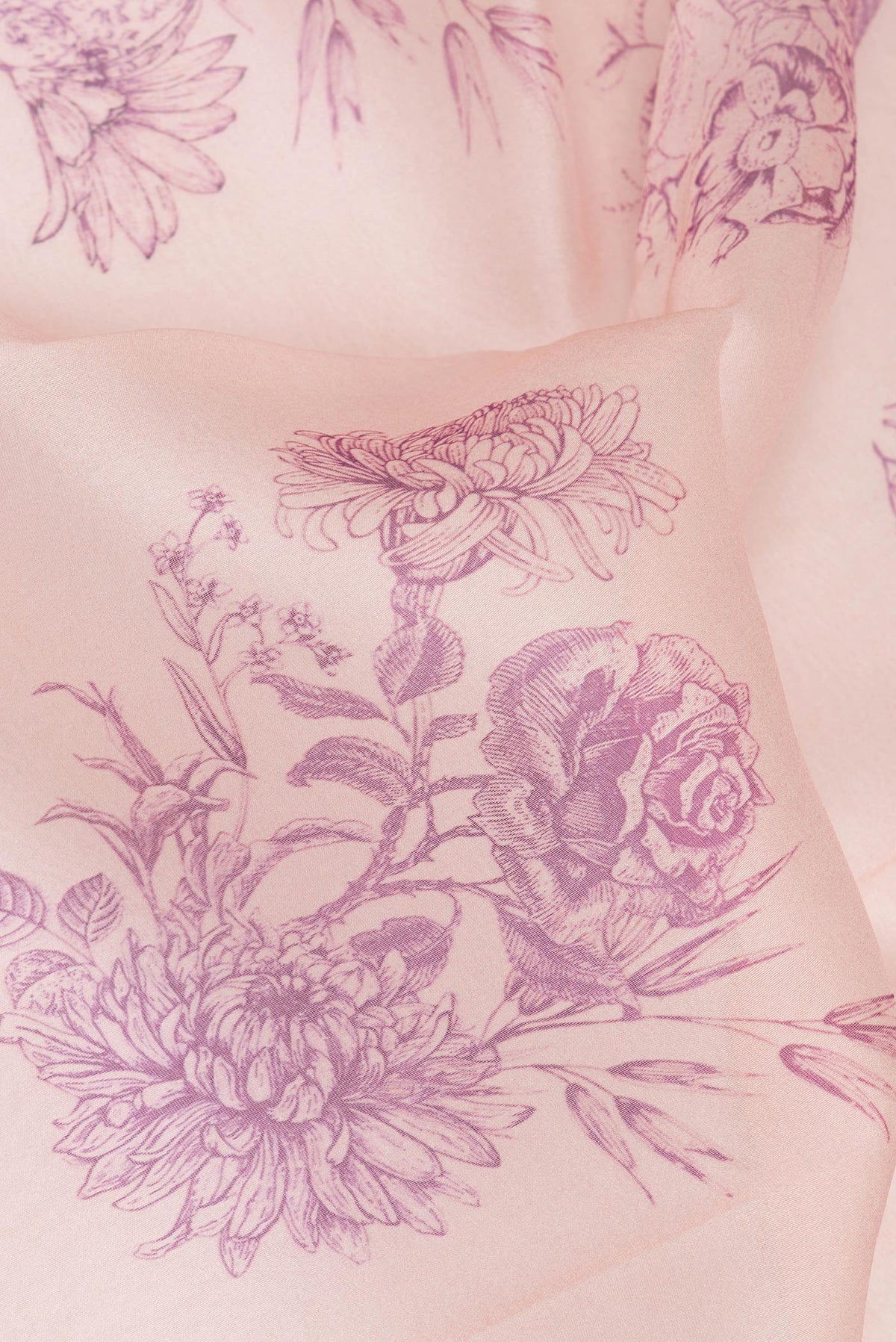 Close up of Rose Gold Organza Saree with Floral Print on the body and Zari Border.  displaying folds