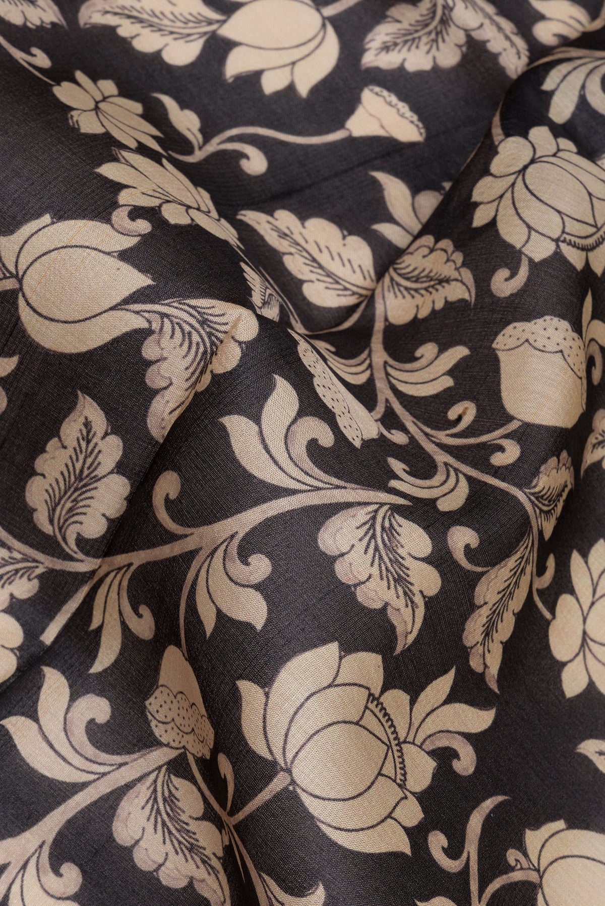 Close up of Black Tussar Saree with Printed design on the body and Zari Border.  displaying folds
