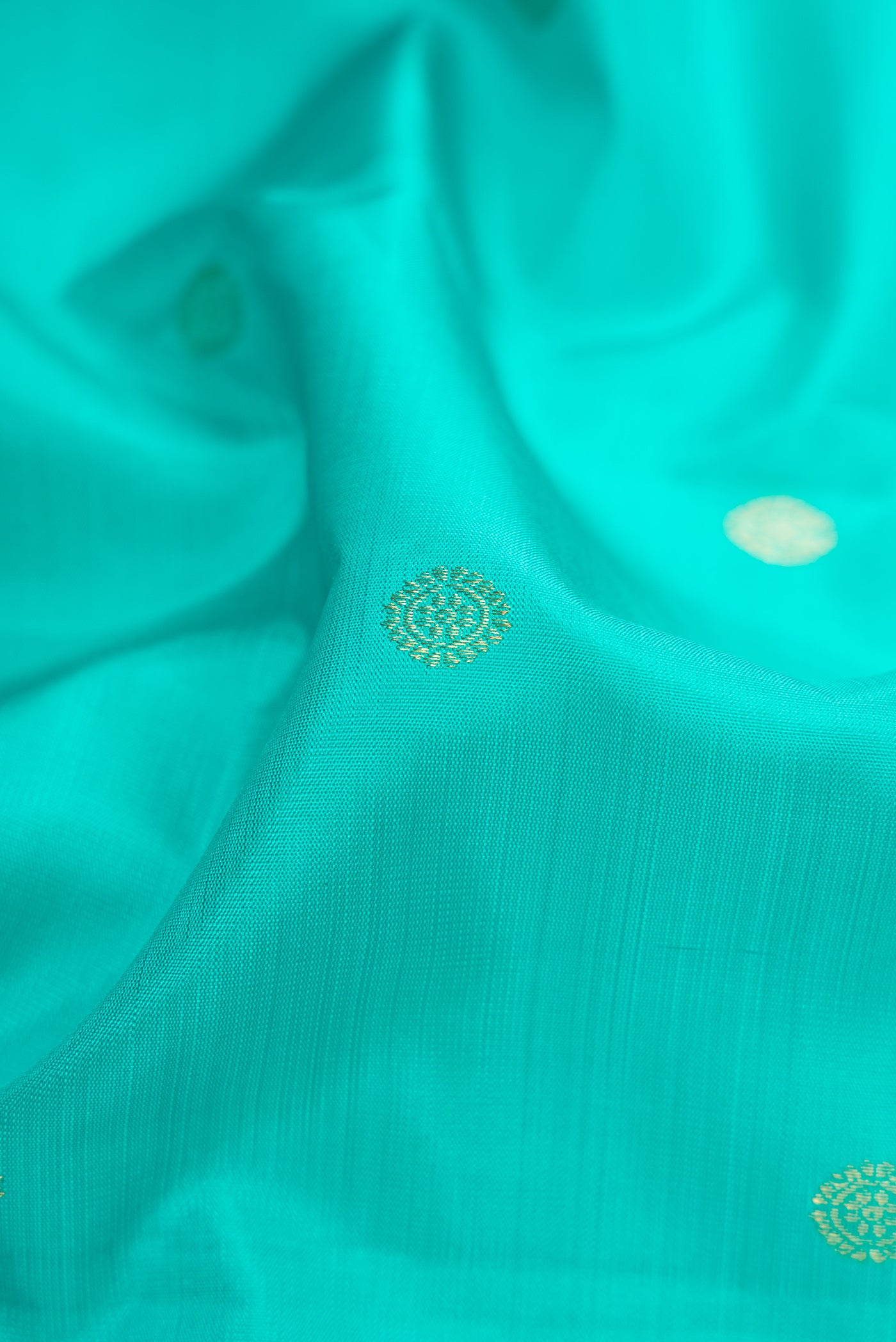 Close up of Turquoise Kanchipuram Silk Saree with Zari Butta on the body and Without Border.  displaying folds