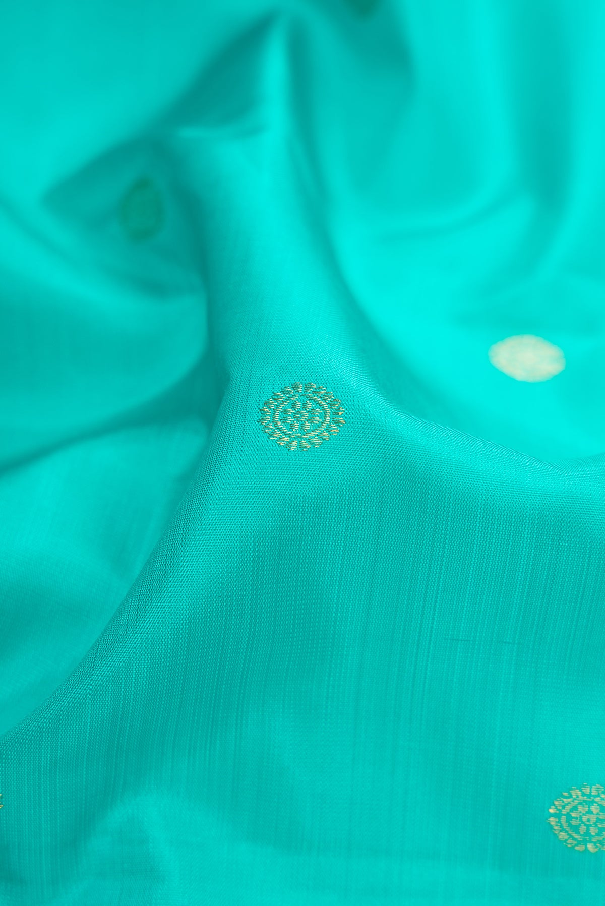 Close up of Turquoise Kanchipuram Silk Saree with Zari Butta on the body and Without Border.  displaying folds