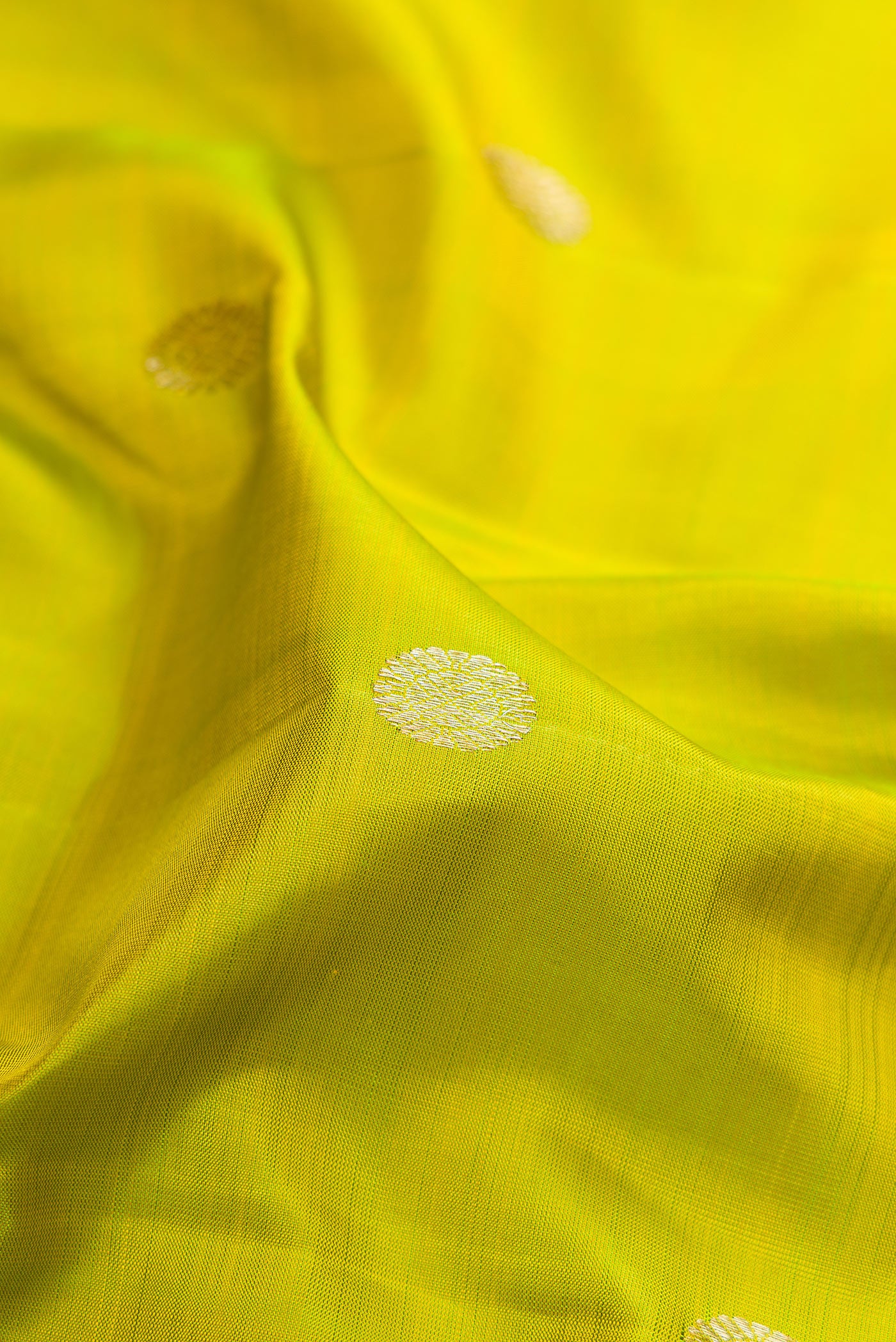 Close up of Parrot Green Kanjivaram Silk Saree with Zari Butta on the body and Zari Border.  displaying folds