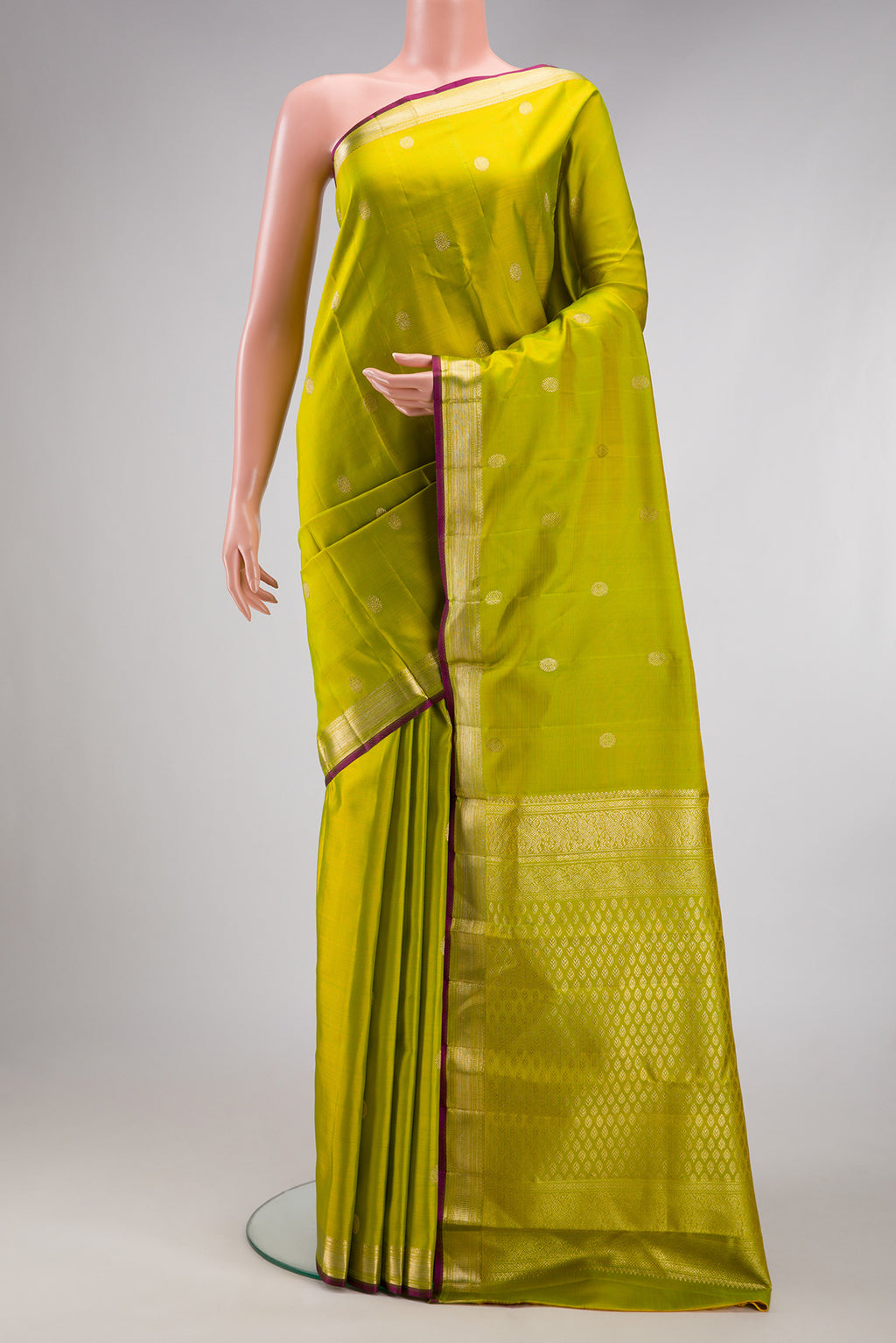 Parrot Green Kanjivaram Silk Saree with Zari Butta on the body and Zari Border.  displayed on a mannequin