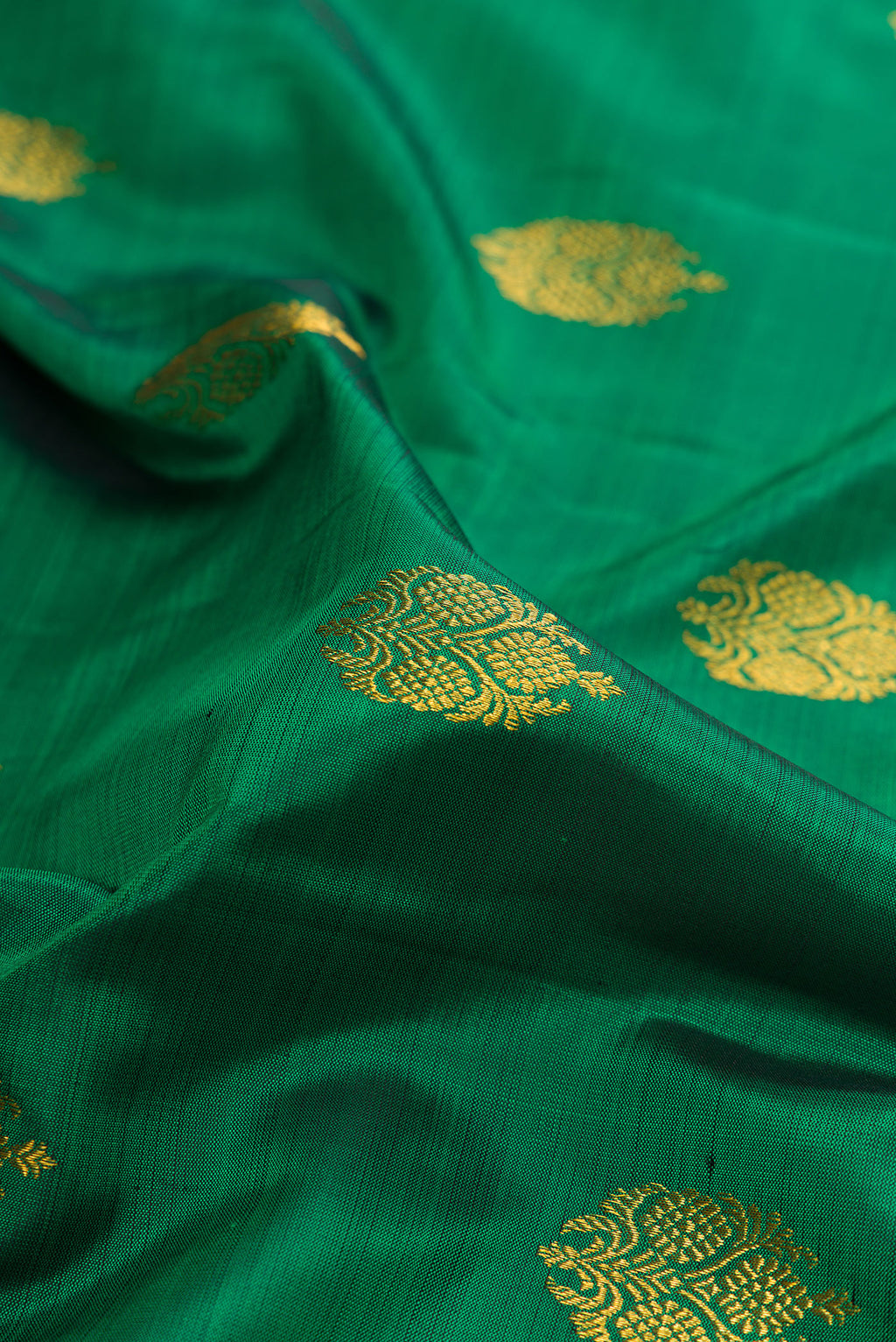 Close up of Green Kanjivaram Silk Saree with Zari Butta on the body and Zari Border.  displaying folds