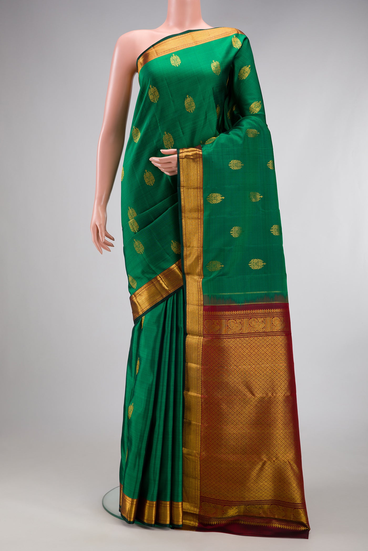 Green Kanjivaram Silk Saree with Zari Butta on the body and Zari Border.  displayed on a mannequin