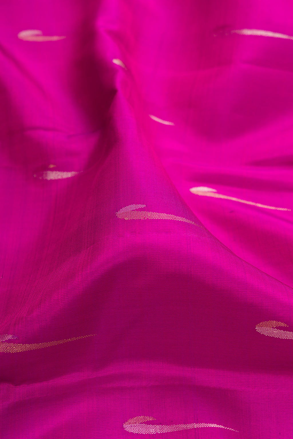 Close up of Magenta Kanchipuram Silk Saree with Zari Butta on the body and Zari Border.  displaying folds
