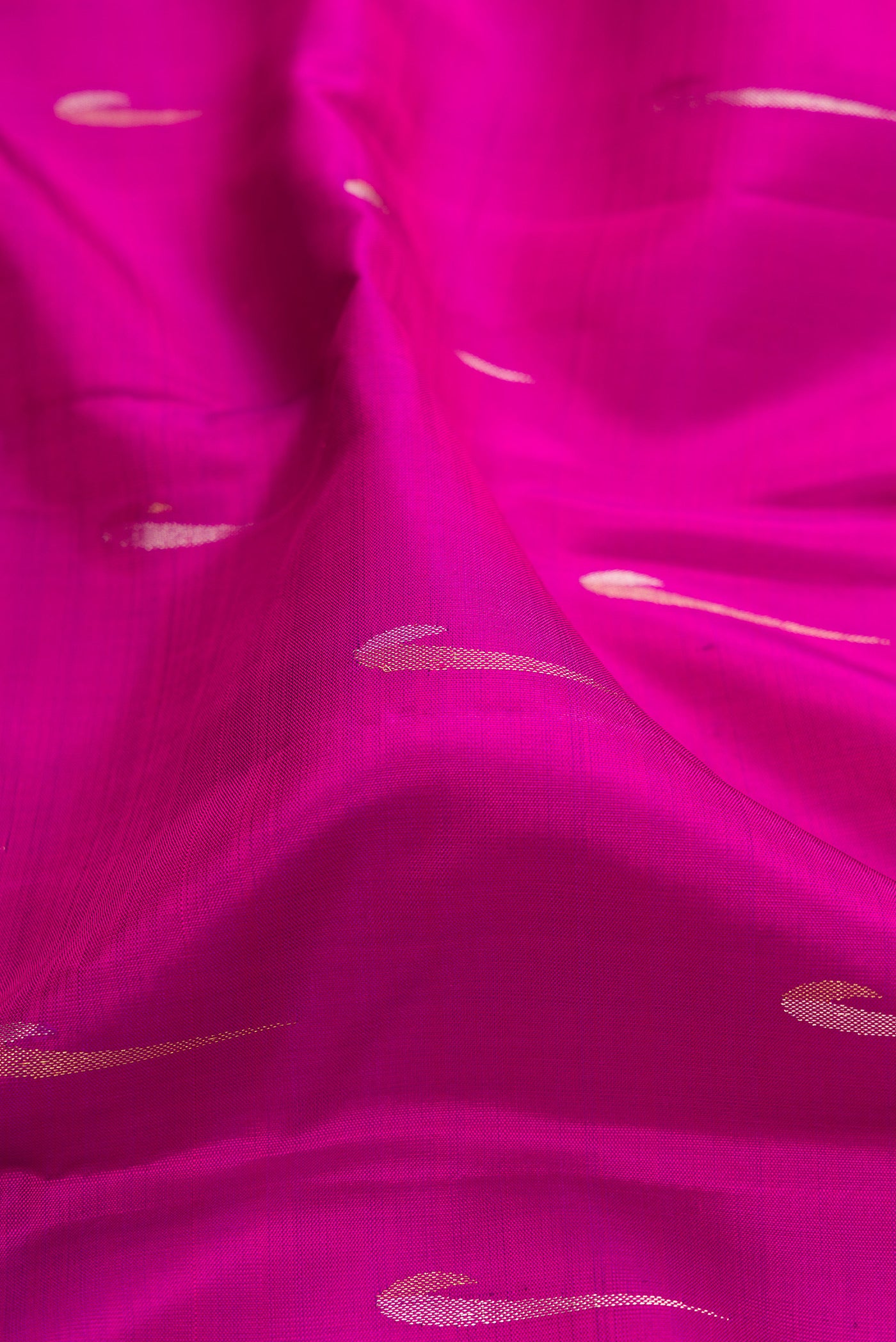 Close up of Magenta Kanchipuram Silk Saree with Zari Butta on the body and Zari Border.  displaying folds