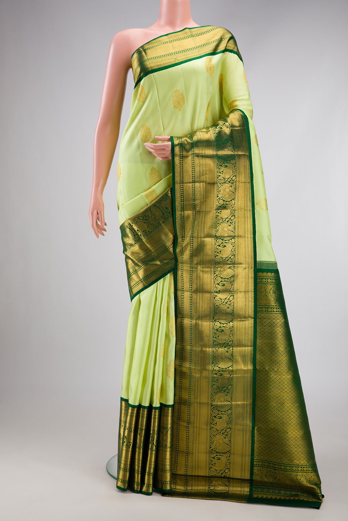 Pista Green Kanchipuram Silk Saree with Zari Butta on the body and Zari Border.  displayed on a mannequin