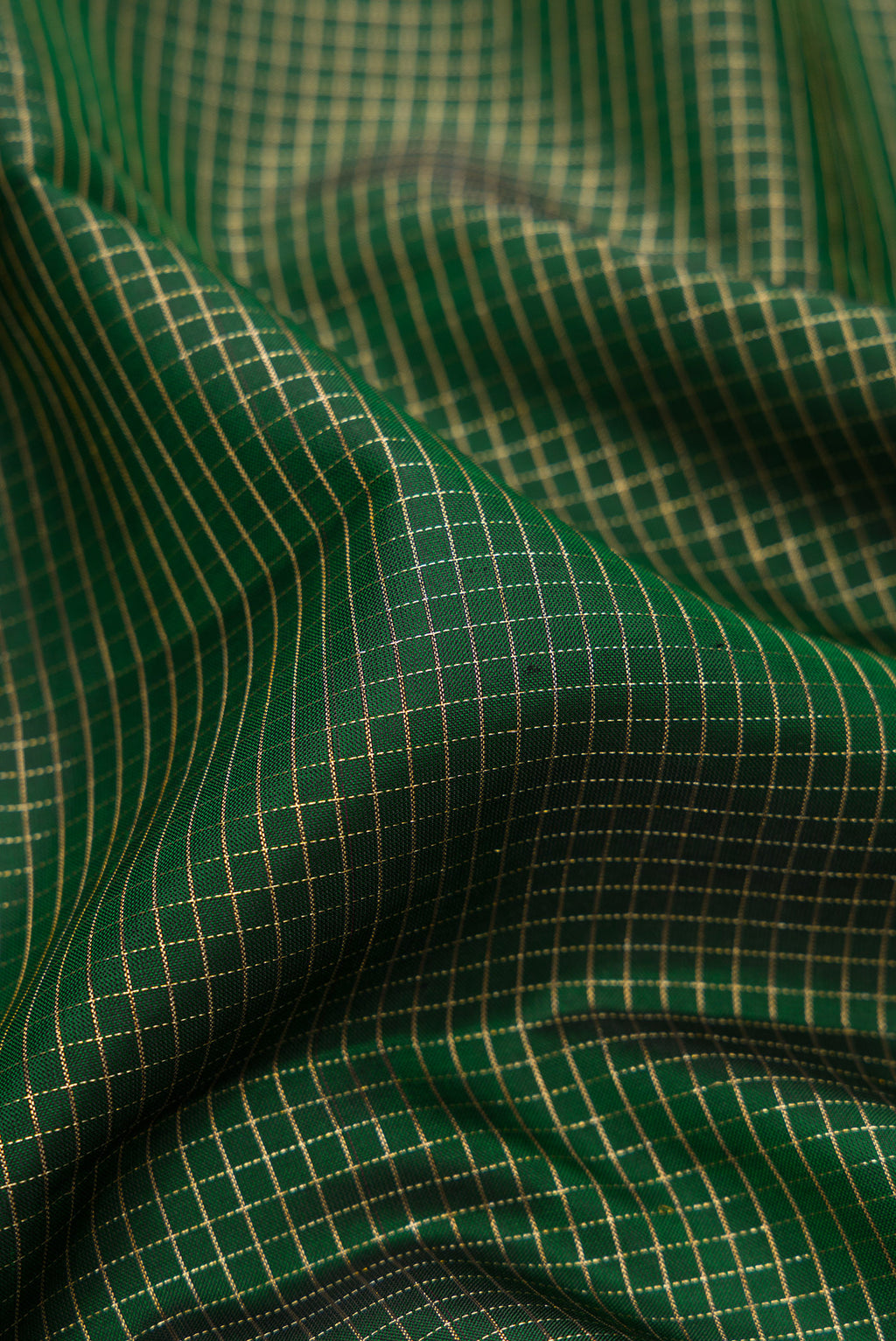 Close up of Bottle Green Kanchipuram Silk Saree with Checked design on the body and Zari Border.  displaying folds