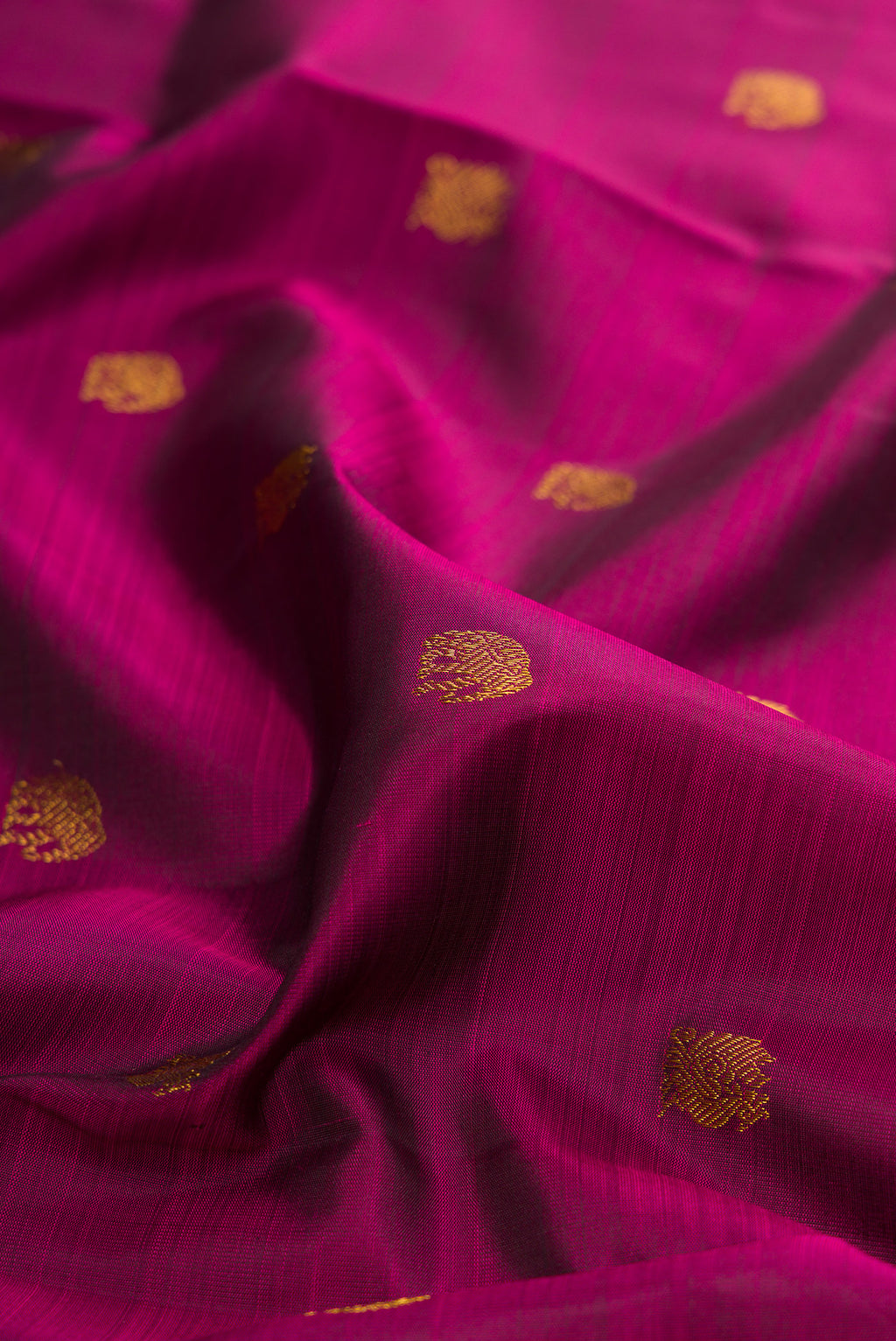 Close up of Magenta Kanchipuram Silk Saree with Zari Butta on the body and Temple Border.  displaying folds