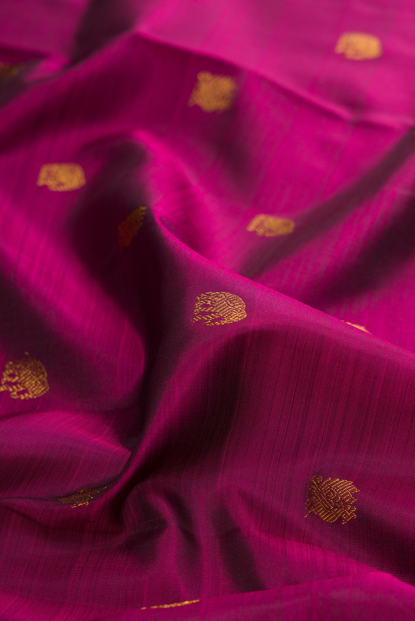 Close up of Magenta Kanchipuram Silk Saree with Zari Butta on the body and Temple Border.  displaying folds