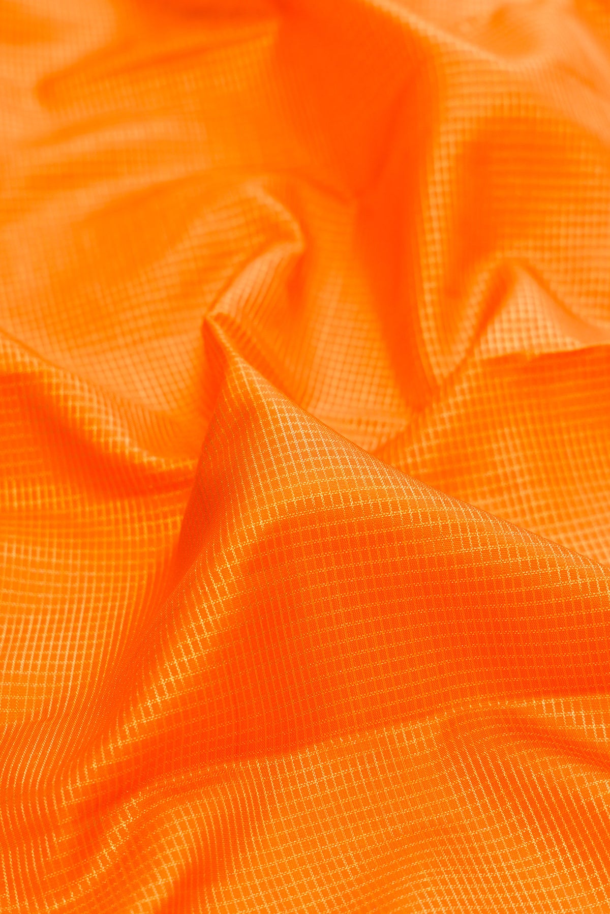 Close up of Pure Silk Orange Kanchipuram Saree with Checked design on the body and Fancy Border.  displaying folds