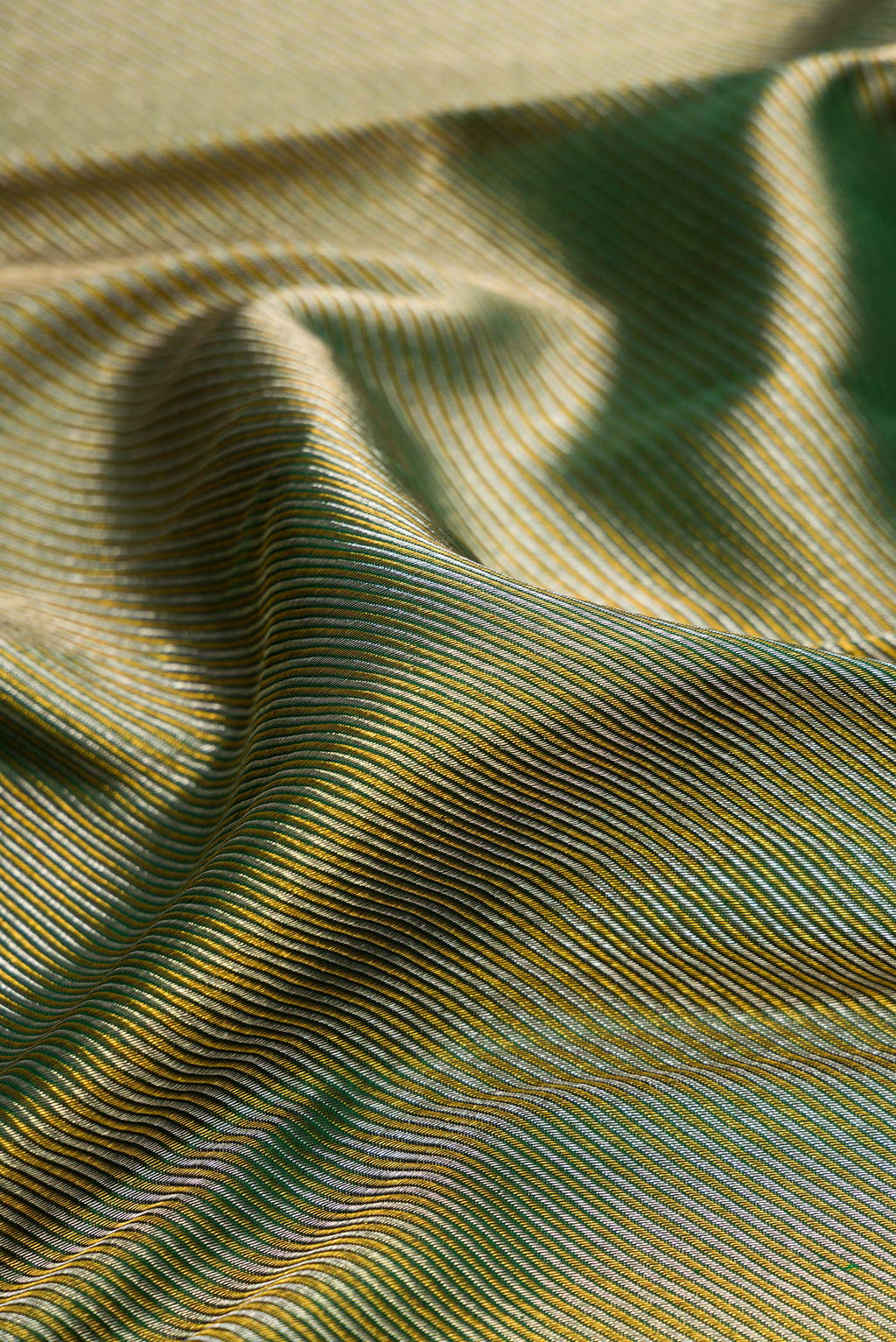 Close up of Pure Silk Bottle Green Kanchipuram Saree with Zari Brocade on the body and Zari Border.  displaying folds
