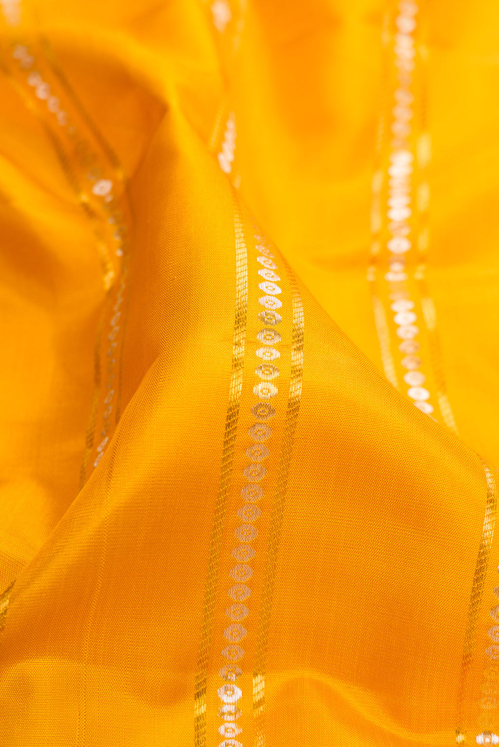 Close up of Yellow Kanchipuram Silk Saree with Stripes on the body and Zari Border.  displaying folds