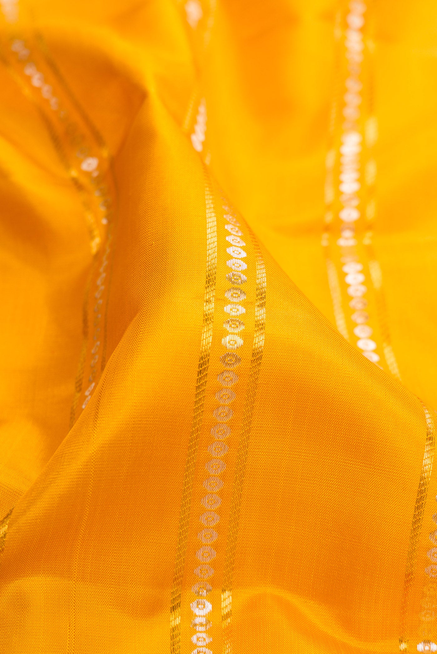 Close up of Yellow Kanchipuram Silk Saree with Stripes on the body and Zari Border.  displaying folds