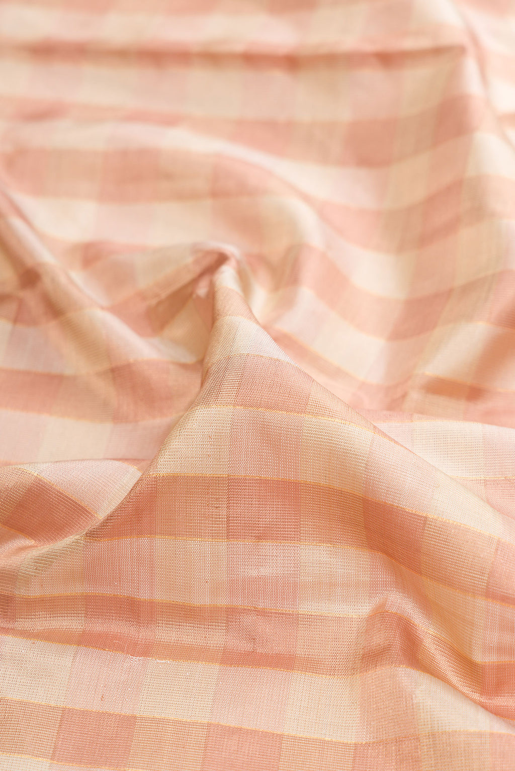 Close up of Pure Silk Rose Gold Dual Tone Kanjivaram Tissue Saree with Checked design on the body and Zari Border.  displaying folds