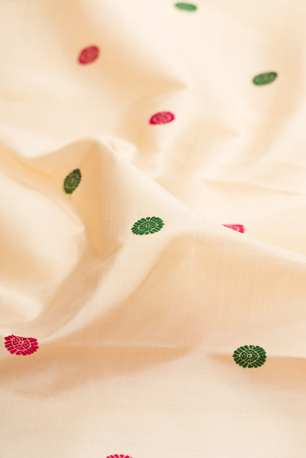 Close up of Beige Kanjivaram Silk Saree with Thread Butta on the body and Zari Border.  displaying folds