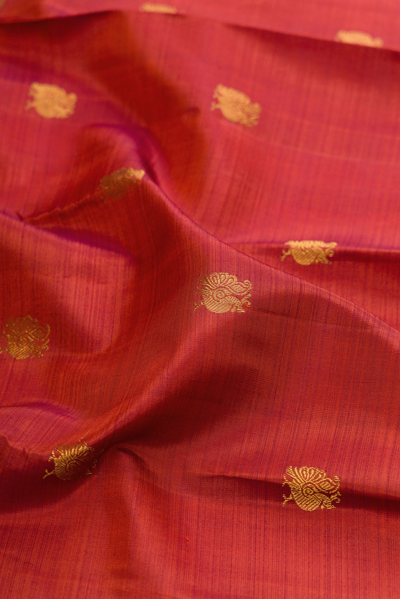 Close up of Brick Orange Dual Tone Kanchipuram Silk Saree with Zari Butta on the body and Zari Border.  displaying folds