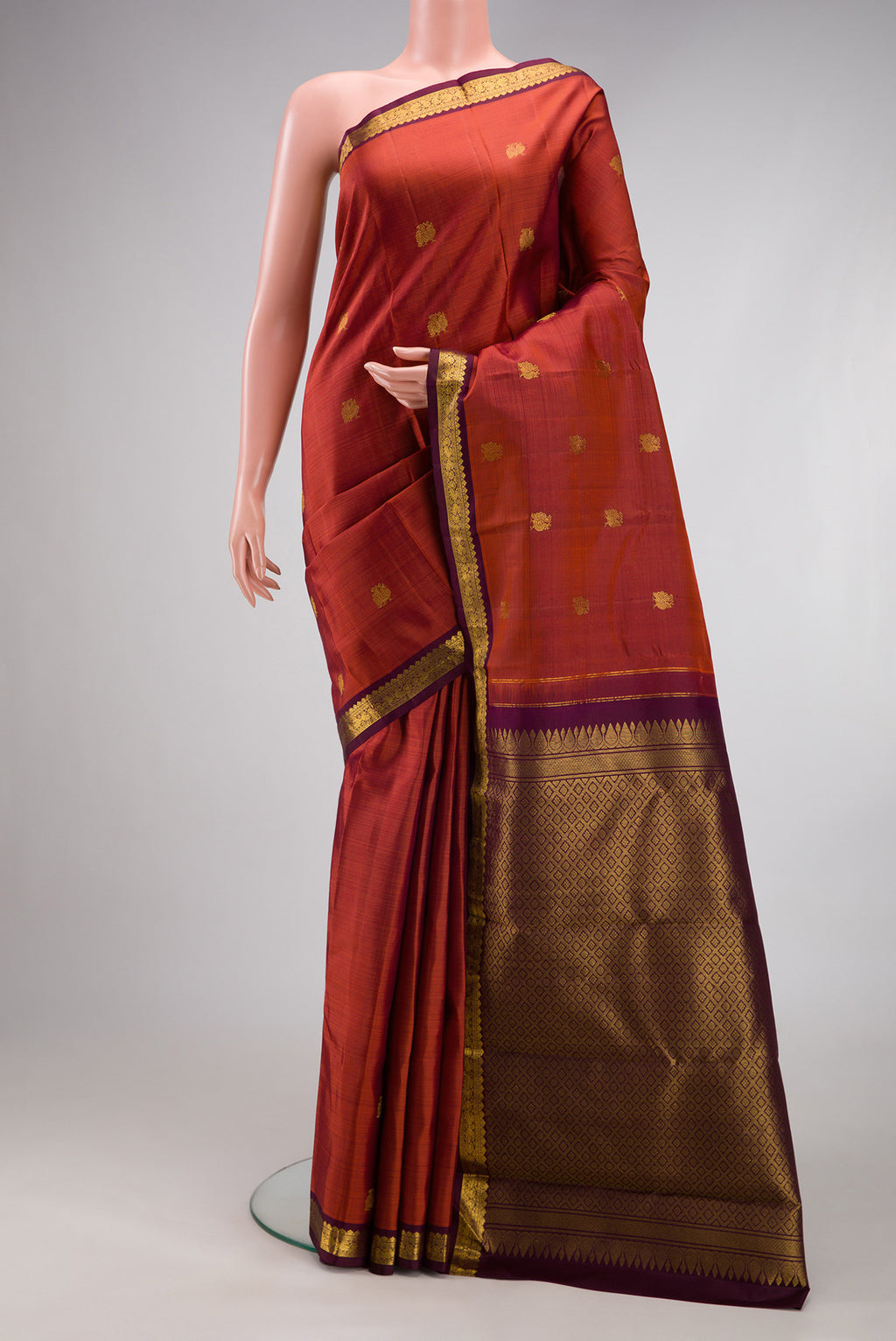 Brick Orange Dual Tone Kanchipuram Silk Saree with Zari Butta on the body and Zari Border.  displayed on a mannequin