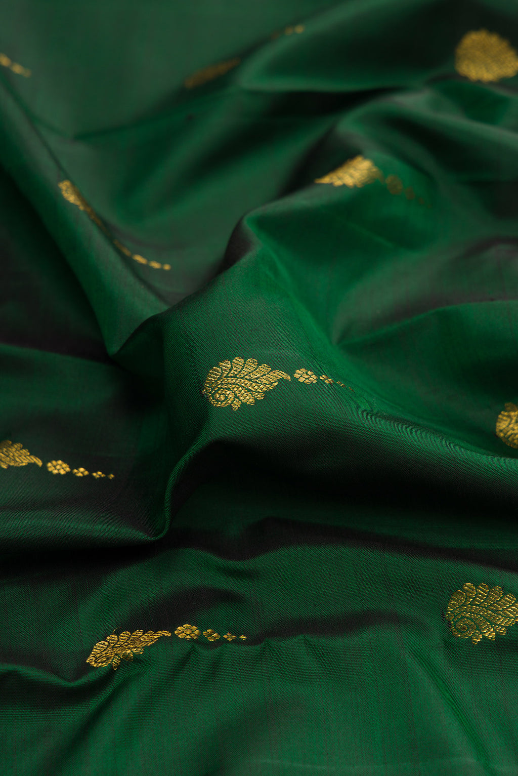 Close up of Pure Silk Bottle Green Kanchipuram Saree with Zari Butta on the body and Zari Border.  displaying folds