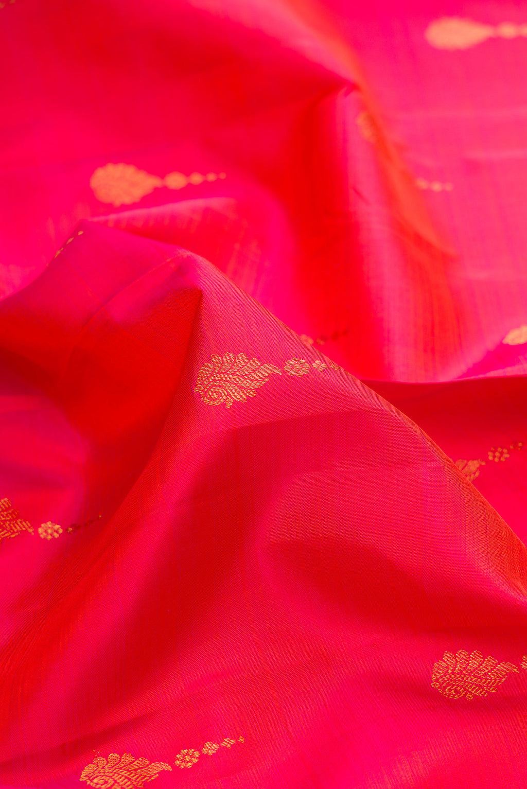 Close up of Pure Silk Coral Dual Tone Kanchipuram Saree with Zari Butta on the body and Zari Border.  displaying folds