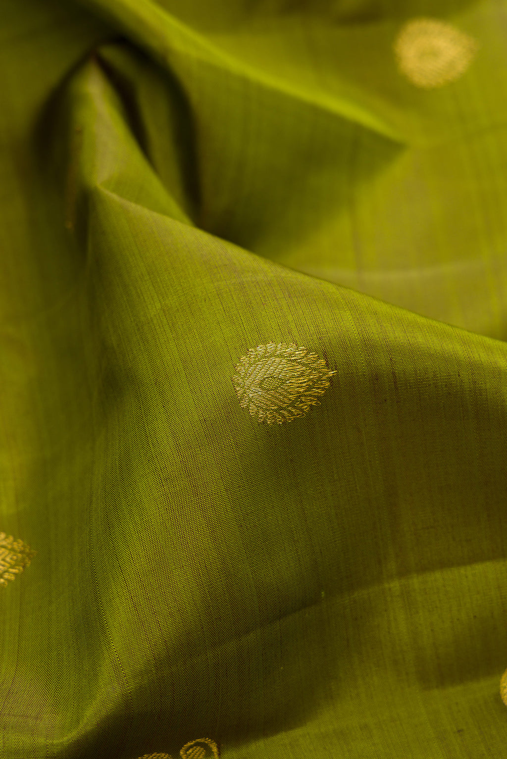Close up of Mehandi Green Kanchipuram Silk Saree with Zari Butta on the body and Zari Border.  displaying folds