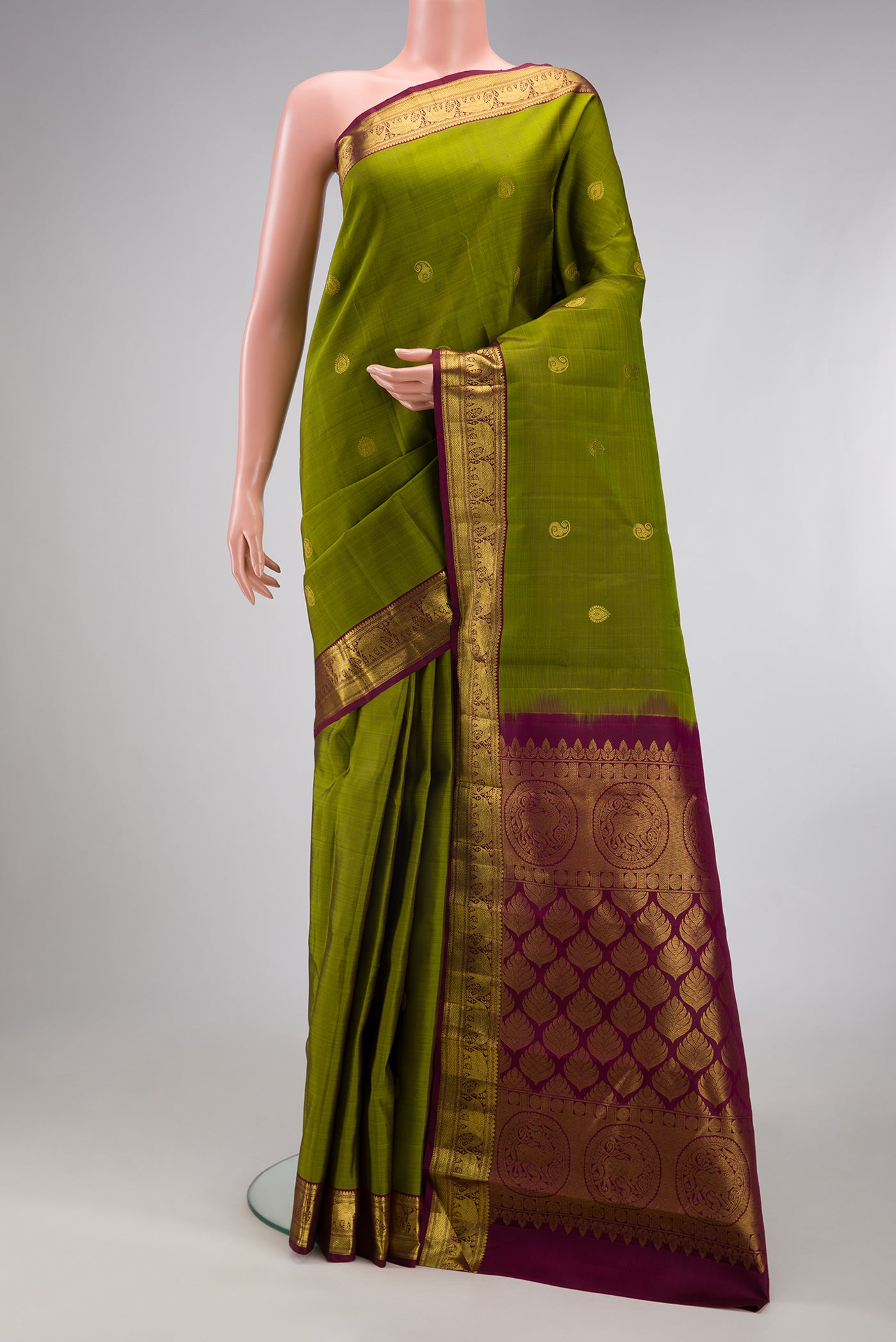 Mehandi Green Kanchipuram Silk Saree with Zari Butta on the body and Zari Border.  displayed on a mannequin