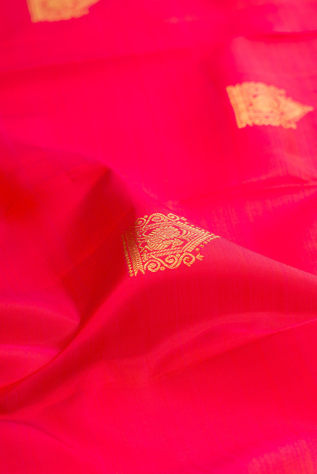 Close up of Dark Pink Dual Tone Kanjivaram Silk Saree with Zari Butta on the body and Zari Border.  displaying folds