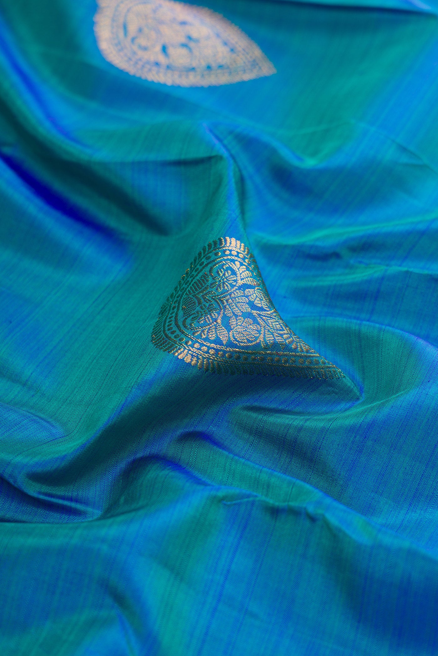 Close up of Peacock Blue Kanjivaram Silk Saree with Zari Butta on the body and Fancy Border.  displaying folds