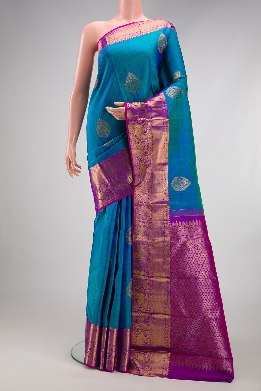 Peacock Blue Kanjivaram Silk Saree with Zari Butta on the body and Fancy Border.  displayed on a mannequin